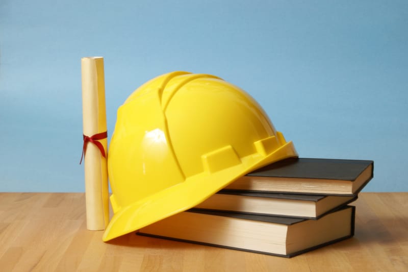 A hard hat, diploma, and books representing trade schools