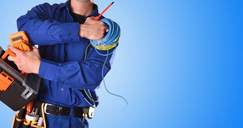 A photo of a tradesperson holding tools and components in front of a blue background