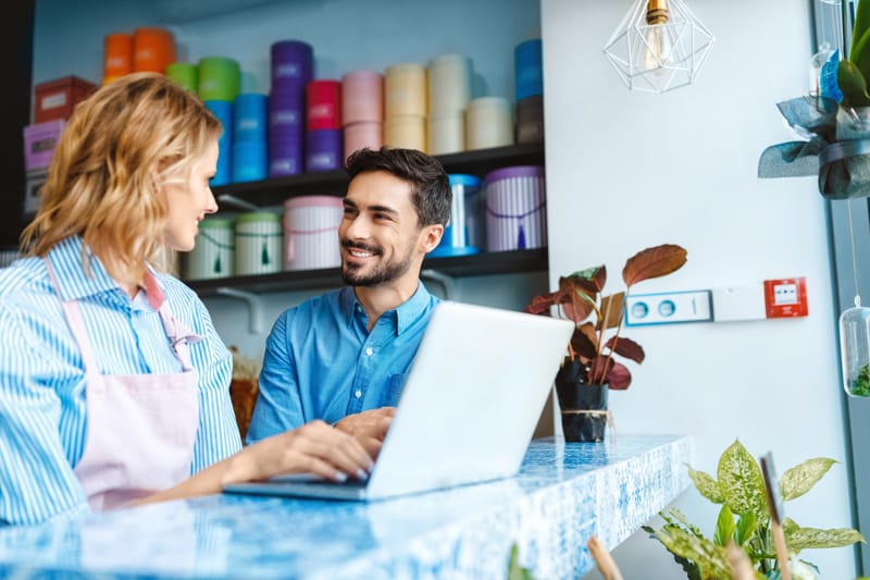 A business owner speaking with a team member at their laptop
