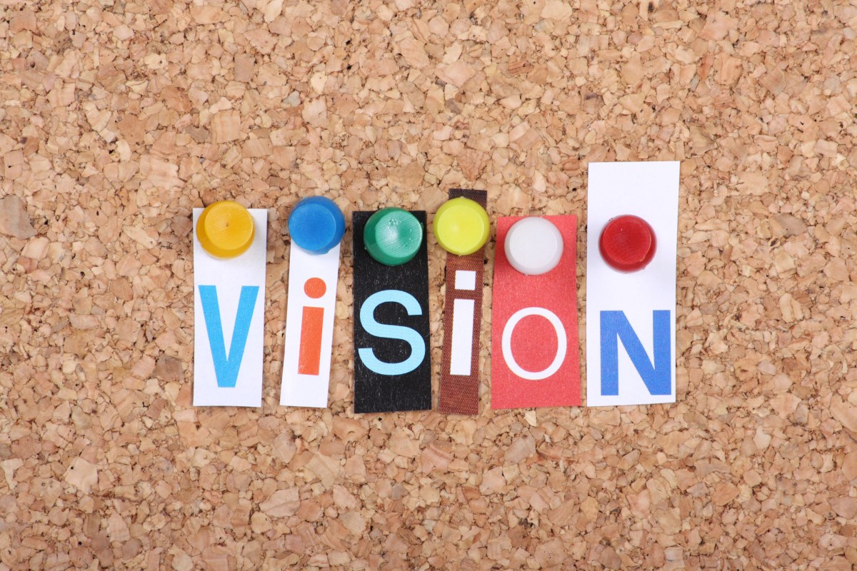 A corkboard with the word VISION on it in magazine clippings