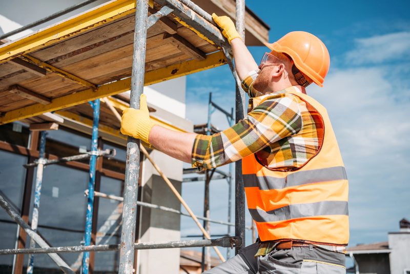 A skilled tradesperson in work clothes reviewing plans on an active construction site